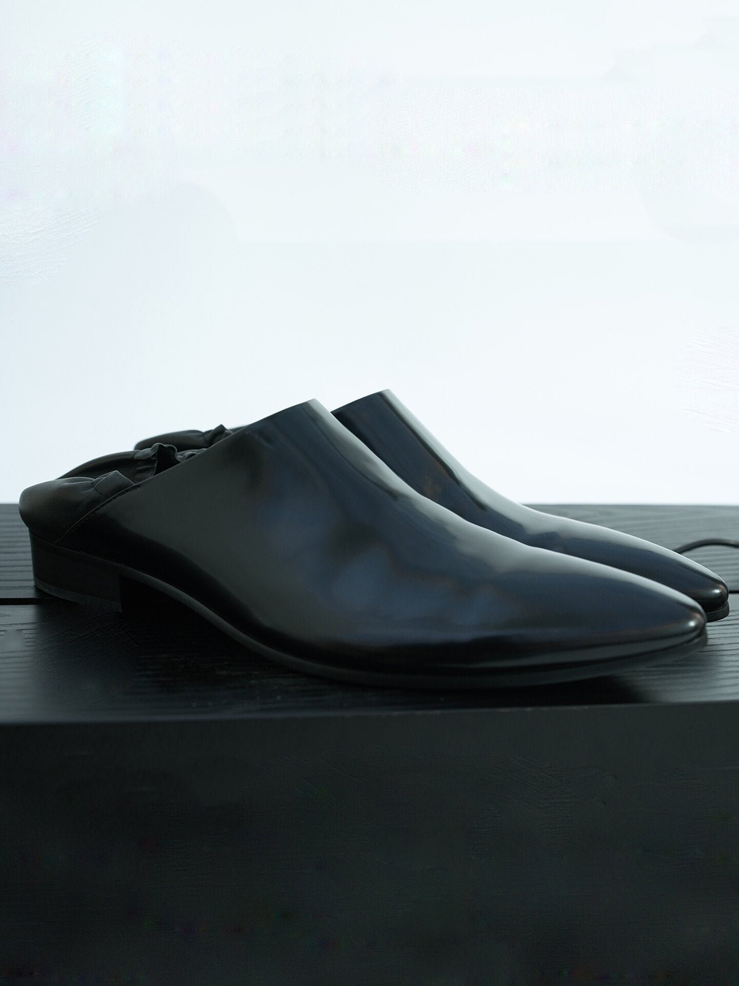 Split‑edge cowhide pointed‑toe black mirror mules